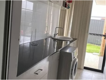 Laundry with a sink, bench and washing machine beside a glass sliding door